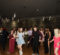 A lively dance floor with people in formal attire enjoying a party, with colorful lights creating a festive atmosphere.