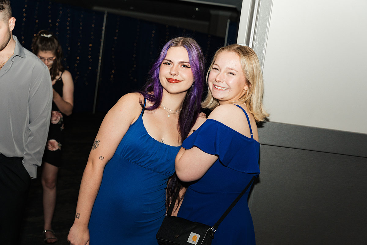 Two female students in dresses smiling for the camera.
