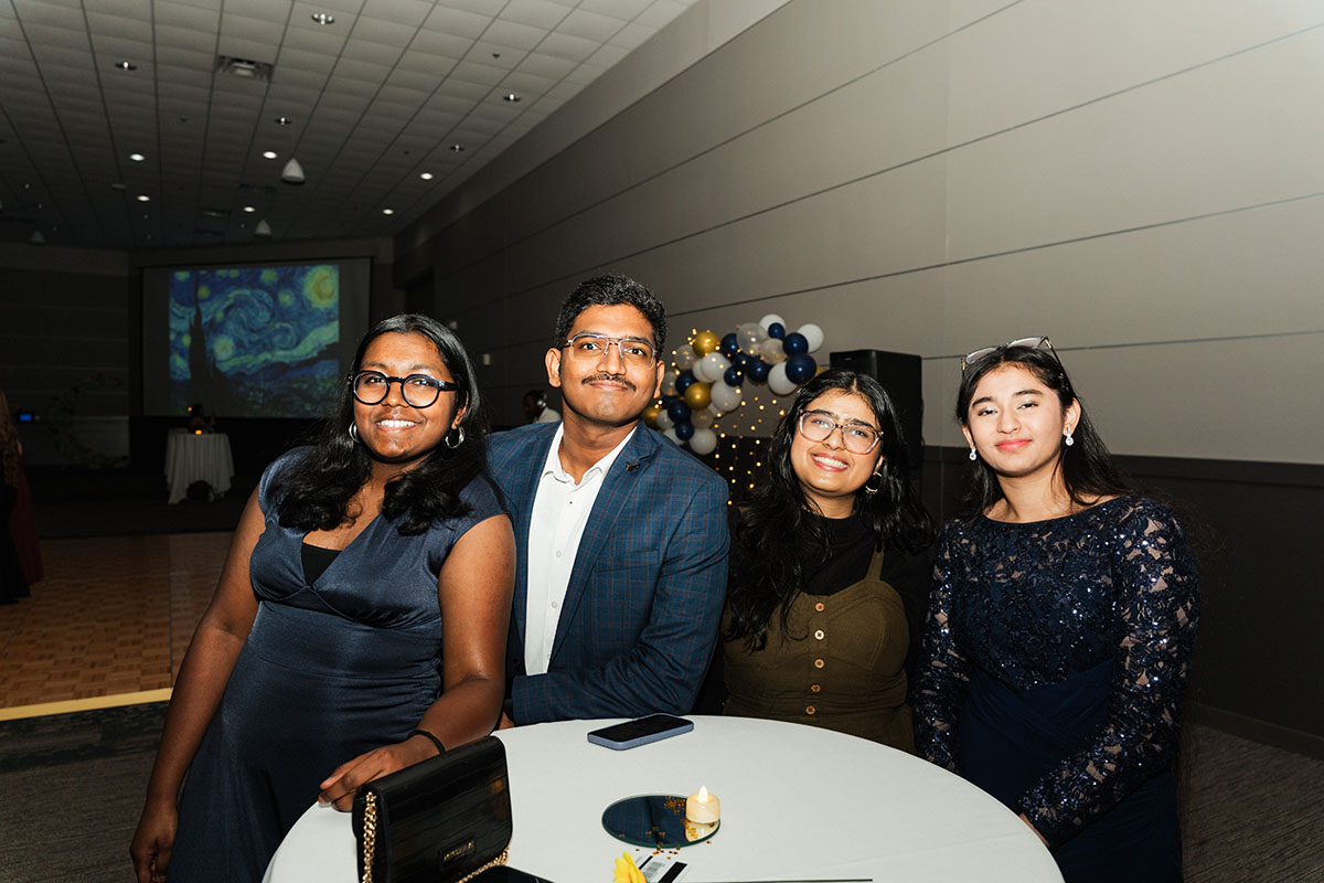 A group of students standig around a table smiling for the camera.