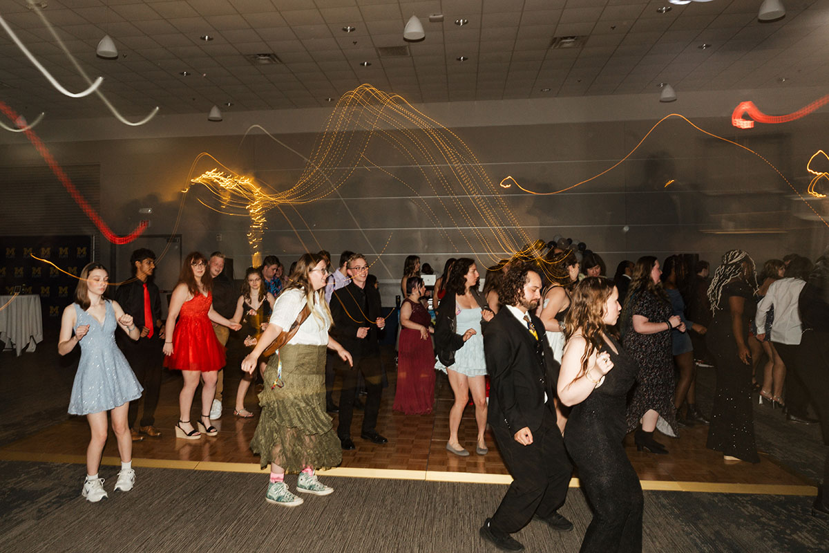 A lively dance floor with people in formal attire enjoying a party, with colorful lights creating a festive atmosphere.