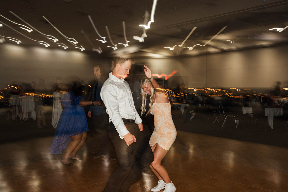 A lively dance floor with people in formal attire enjoying a party, with colorful lights creating a festive atmosphere.
