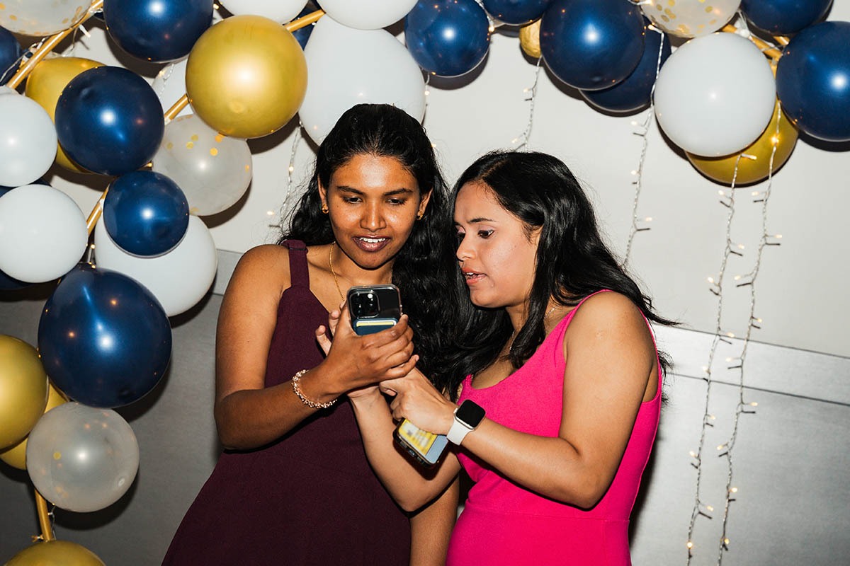 Two female students looking at a photo they just took on their phones.