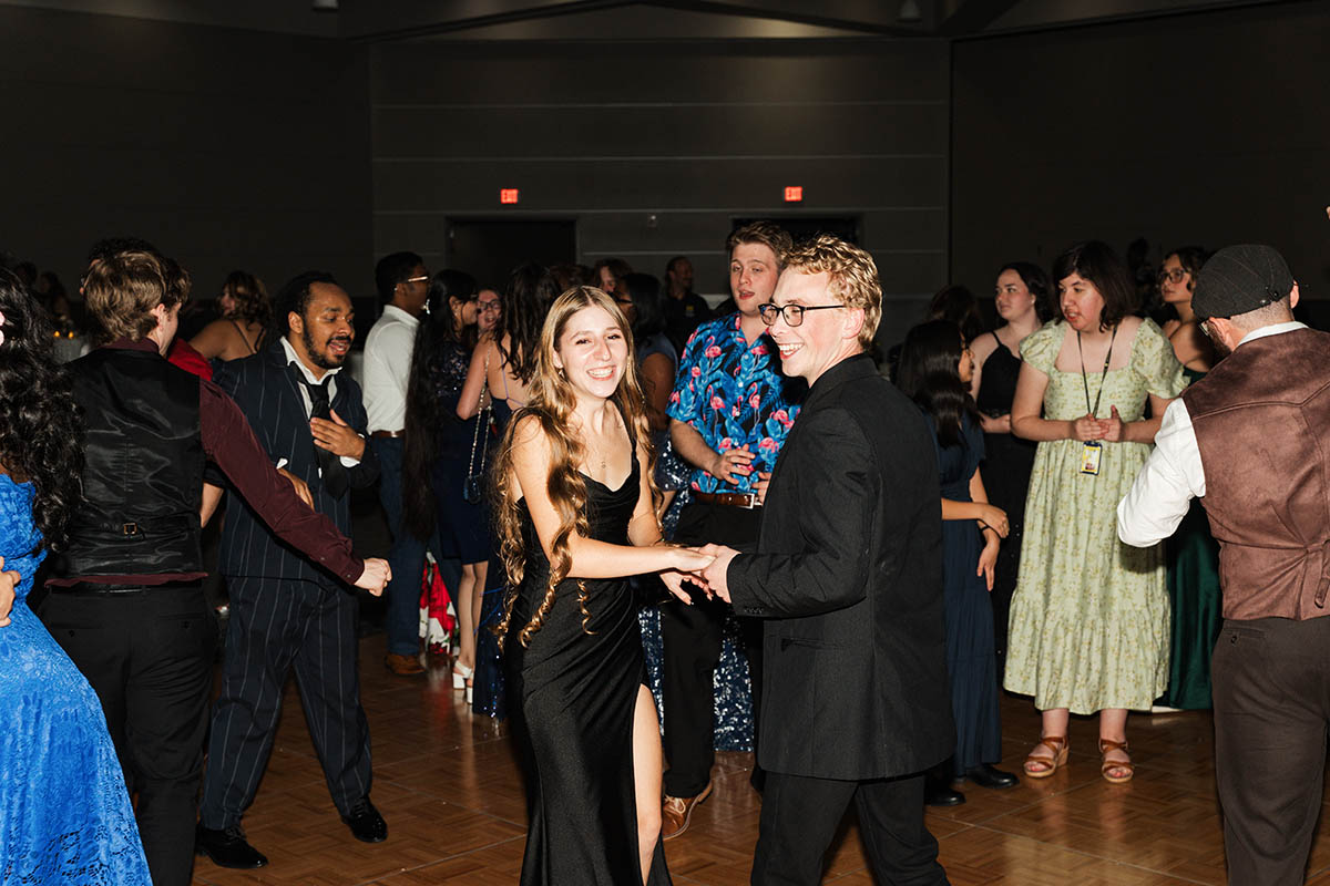 A lively dance floor with people in formal attire enjoying a party, with colorful lights creating a festive atmosphere.