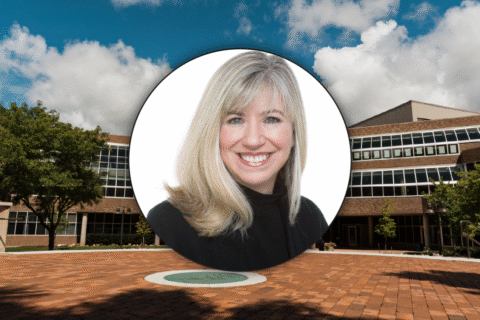 A circular portrait of a woman with long, blonde hair, set against a background of a modern building and blue sky.