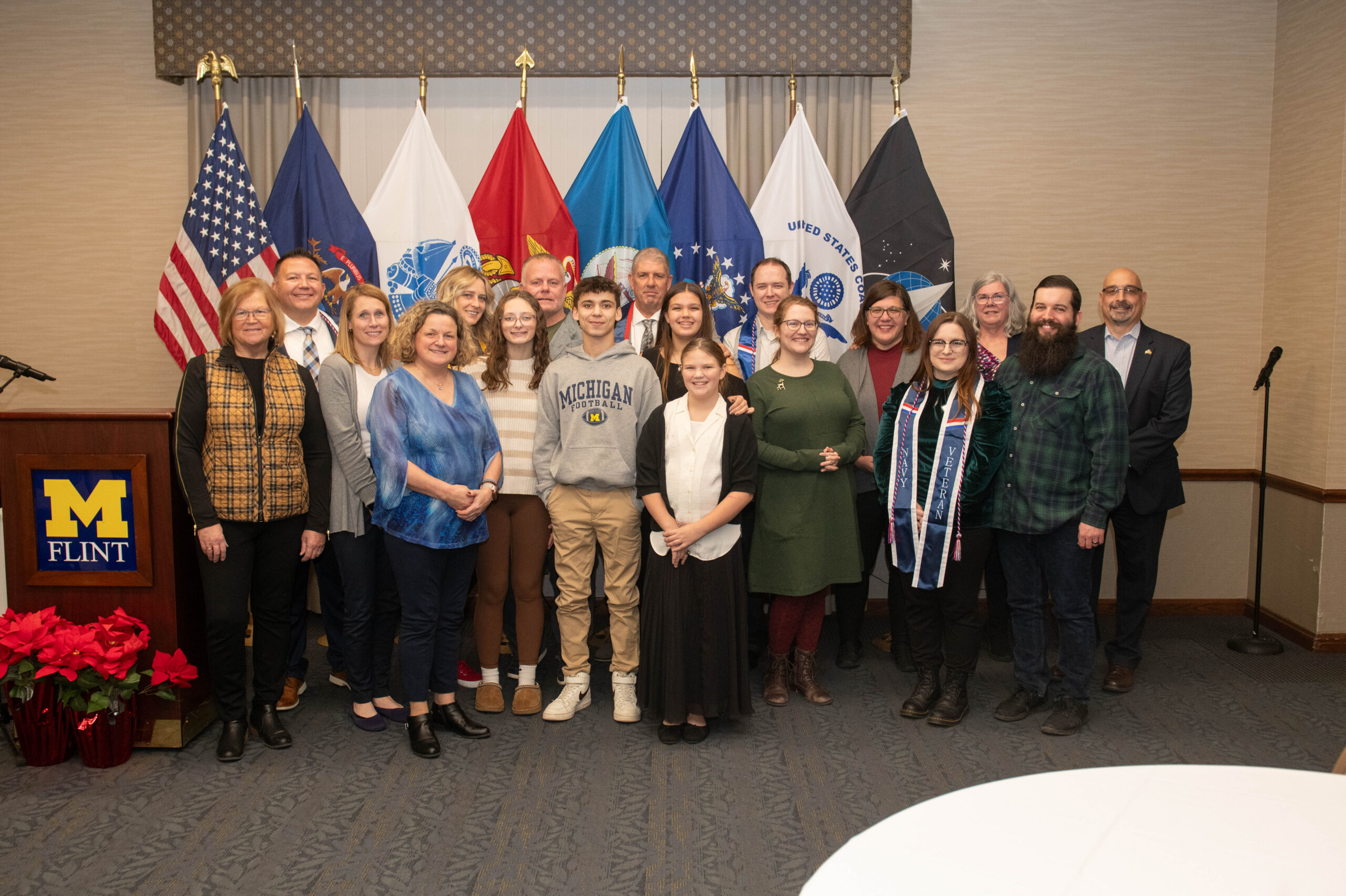 Student veterans and their families pose with support staff during a veteran graduation ceremony.