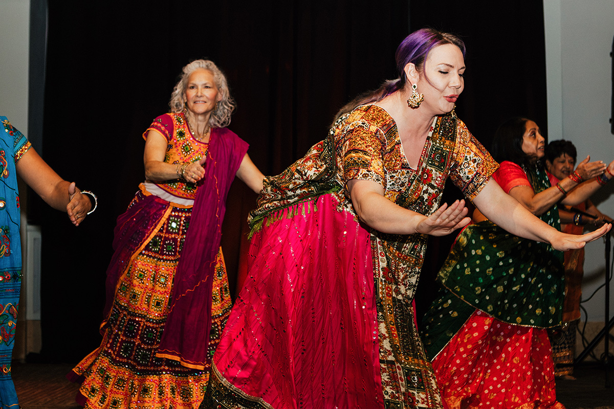 A group of women in colorful traditional attire performing a dance on stage.