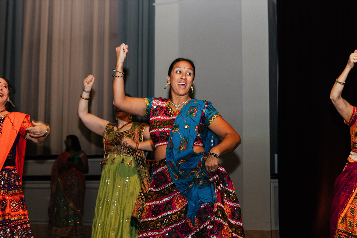 A group of women dressed in colorful traditional attire dancing joyfully at an event.