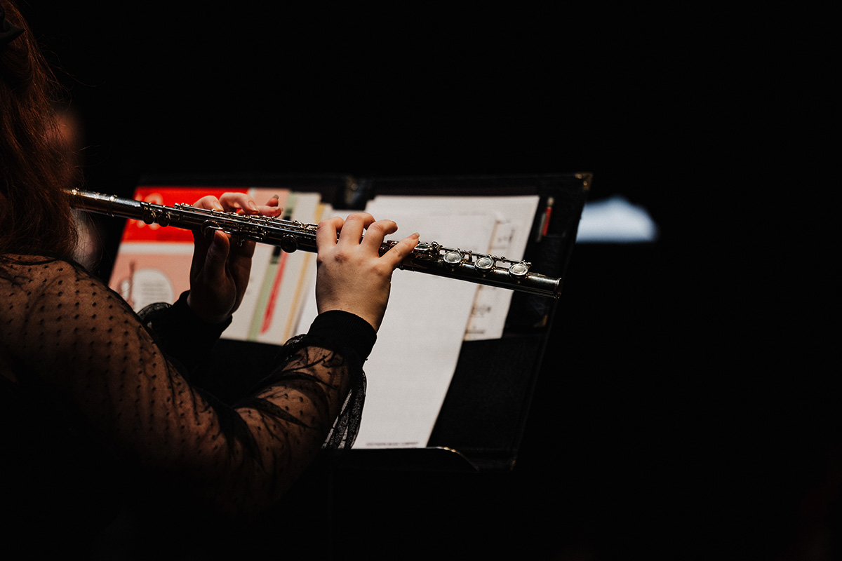 A musician playing a flute, with sheet music visible in the background.