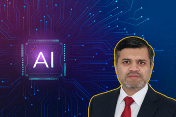 A man in a suit stands beside a graphic of a microchip with the text "AI" on it, set against a circuit board background.