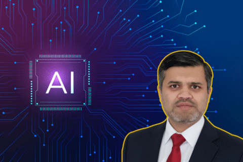 A man in a suit stands beside a graphic of a microchip with the text "AI" on it, set against a circuit board background.