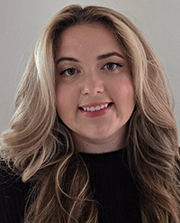 A person with long, wavy blonde hair wearing a black top.