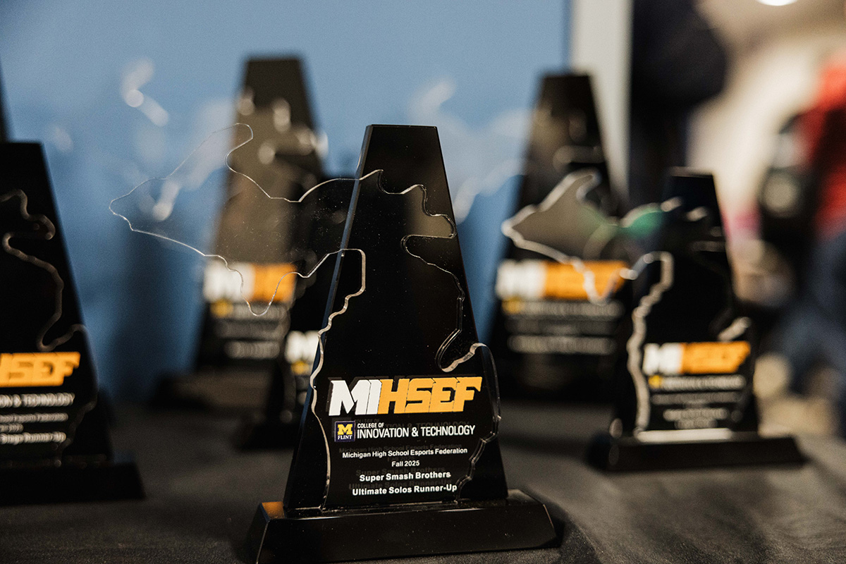 A close-up of several black trophies shaped like the state of Michigan, featuring text that reads "MHSEF College of Innovation & Technology Michigan High School Esports Federation Fall 2025 Super Smash Brothers Ultimate Solos Runner-Up."