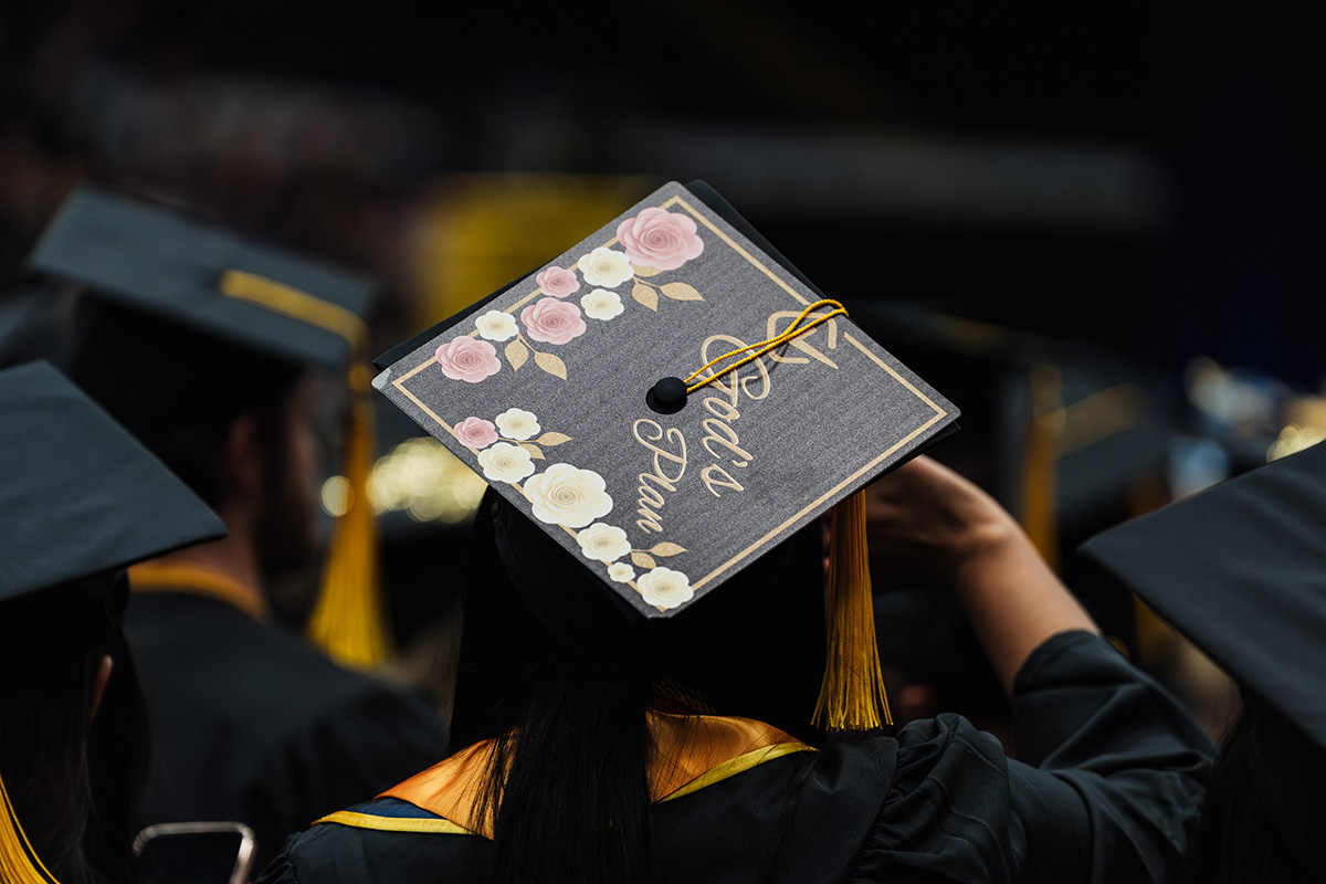 A graduation cap decorated with flowers and the text "God's Plan," with a tassel hanging from the side.