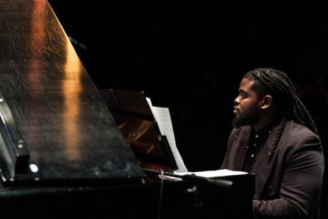 A student sitting and playing at a piano