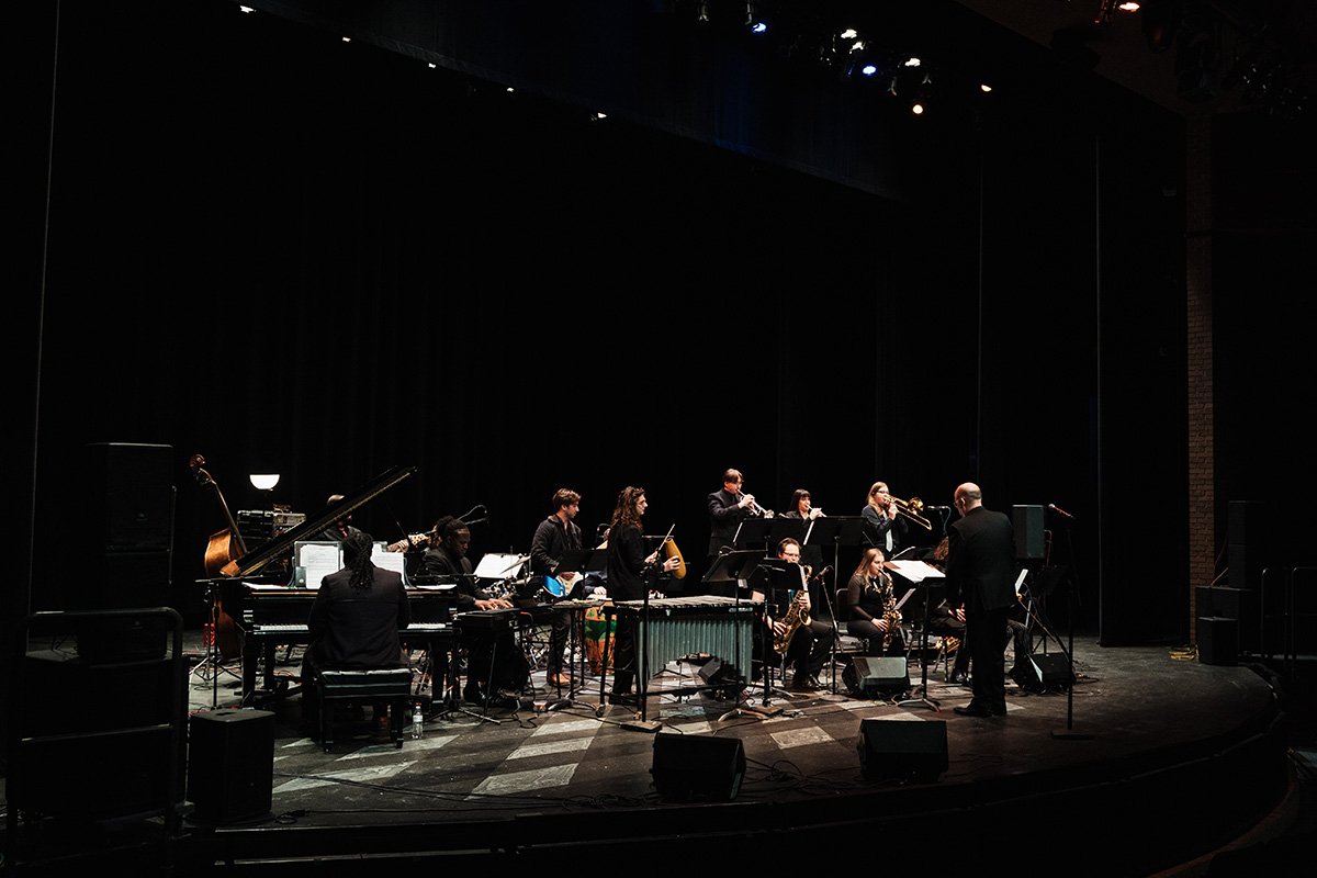 A jazz band performing on stage with various instruments, including a piano, saxophones, and brass instruments.