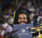 A graduate wearing a cap and gown holds a diploma from the University of Michigan during a graduation ceremony.