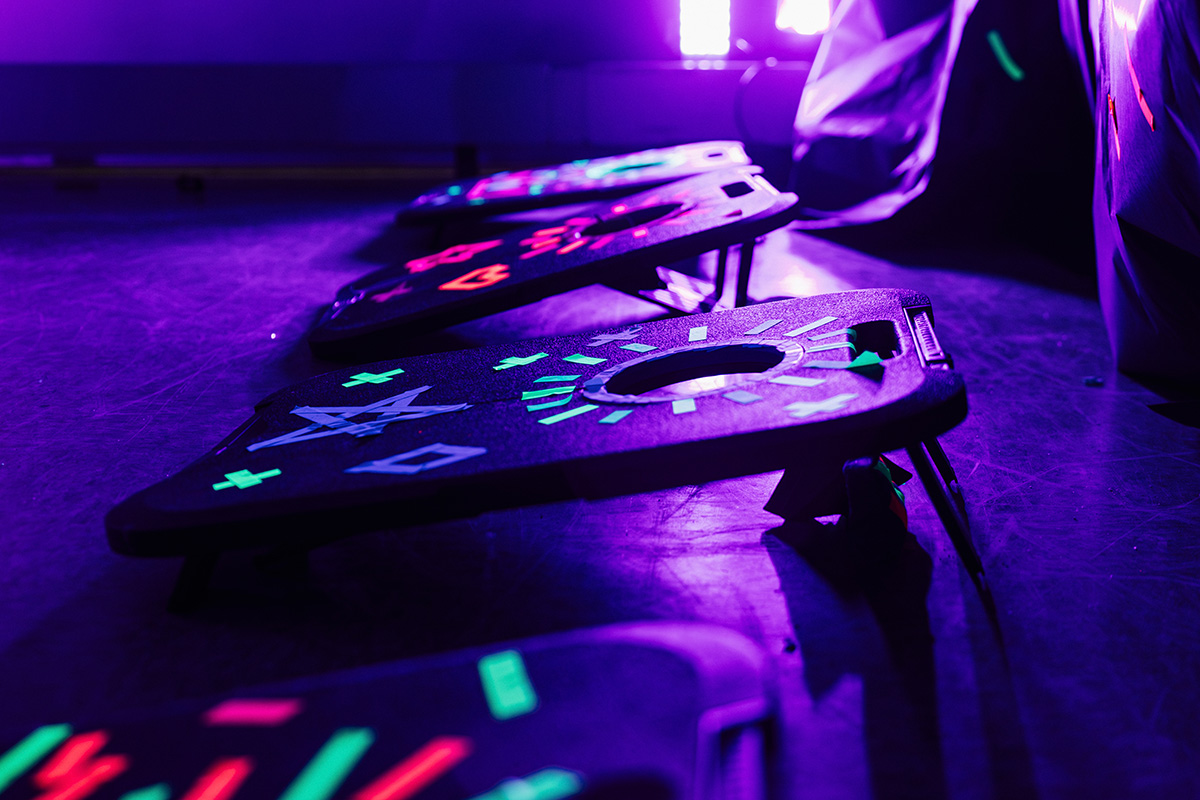 FLINT_Light Up the Night 2026_0002 A row of illuminated gaming boards with various colorful symbols, set against a purple-lit background.