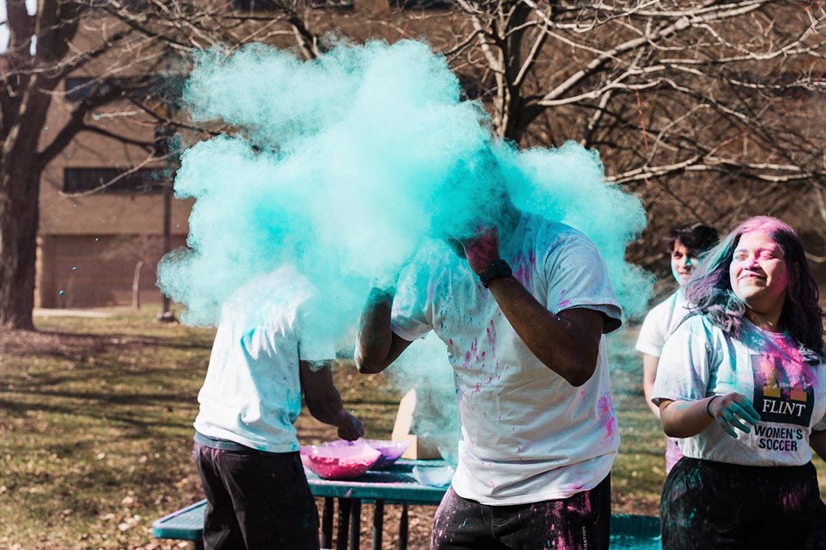 People outdoors throwing colored powder during a color run or festival event.