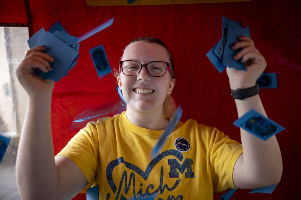 A student smiling while holding mock money in the cash cube.