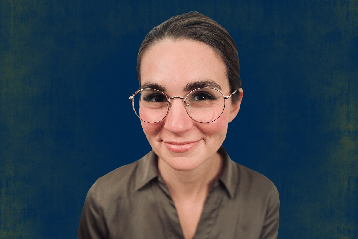 Person wearing glasses and a brown shirt against a dark blue background with a greenish texture.