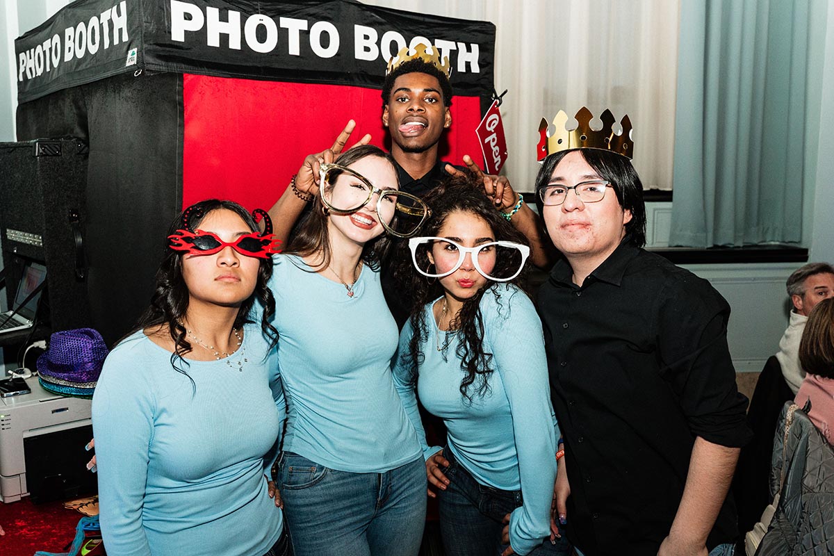 FLINT_LUNA Quinceañera Night 2026_0043 Group of five people posing in front of a photo booth, some wearing crowns and novelty glasses.