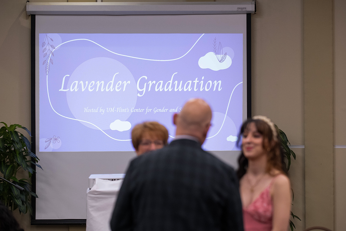 FLINT_Lavender Graduation Celebration 2026_0002 People attending a Lavender Graduation event with a purple presentation screen in the background.