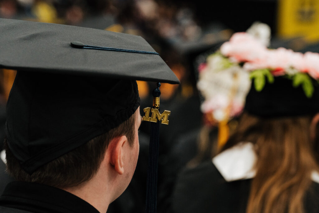 A shot from behind of a graduate's cap with the "1M" tassel charm