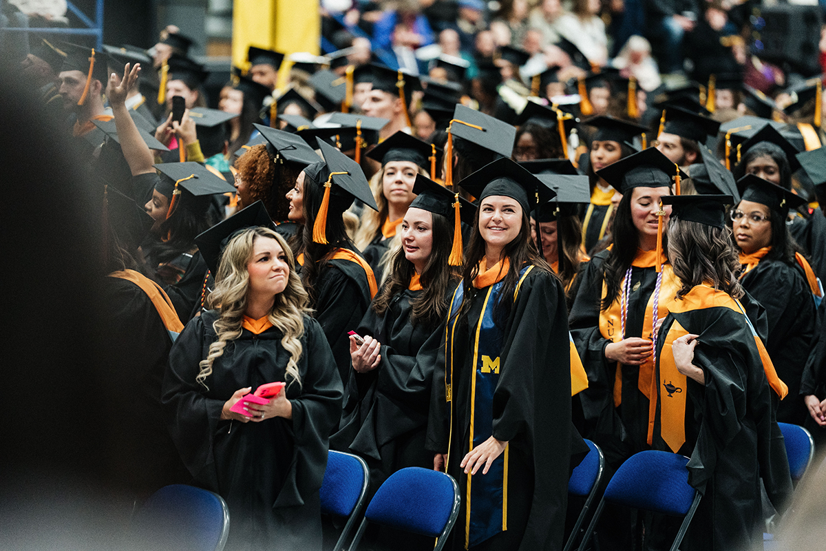 FLINT_Winter Commencement April 2026_0210 Group of graduates in caps and gowns standing indoors during a ceremony
