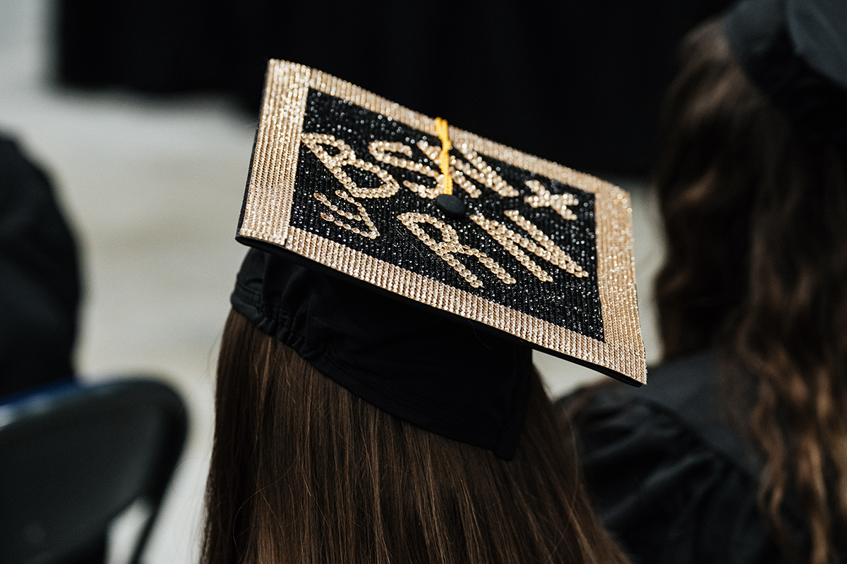 FLINT_Winter Commencement Caps April 2026_0004 Graduation cap decorated with gold and black rhinestones spelling "BSN RN" on a graduate's head.