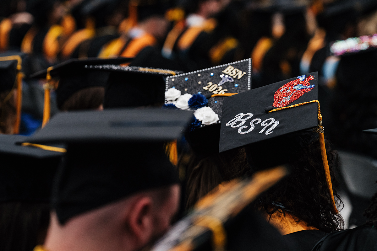FLINT_Winter Commencement Caps April 2026_0009 Graduates wearing decorated caps, two caps prominently display "BSN" with one featuring a red anatomical heart and the other with flowers and "2024".