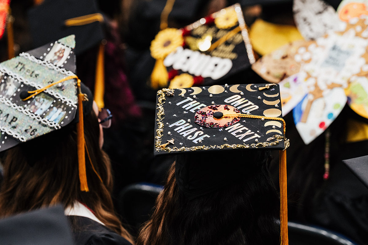 FLINT_Winter Commencement Caps April 2026_0054 Graduation cap decorated with moons and a donut, with the text "Onto the next phase."
