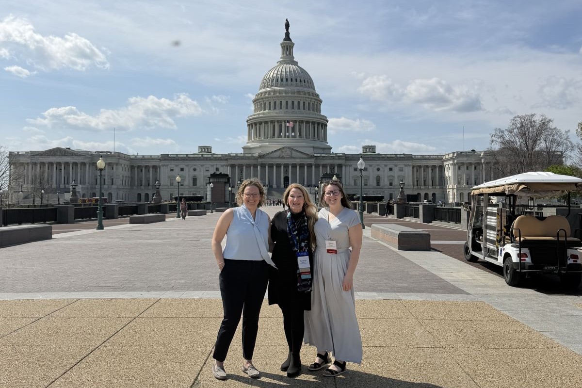 Three people standing in front of the United States Capitol building on a clear day.