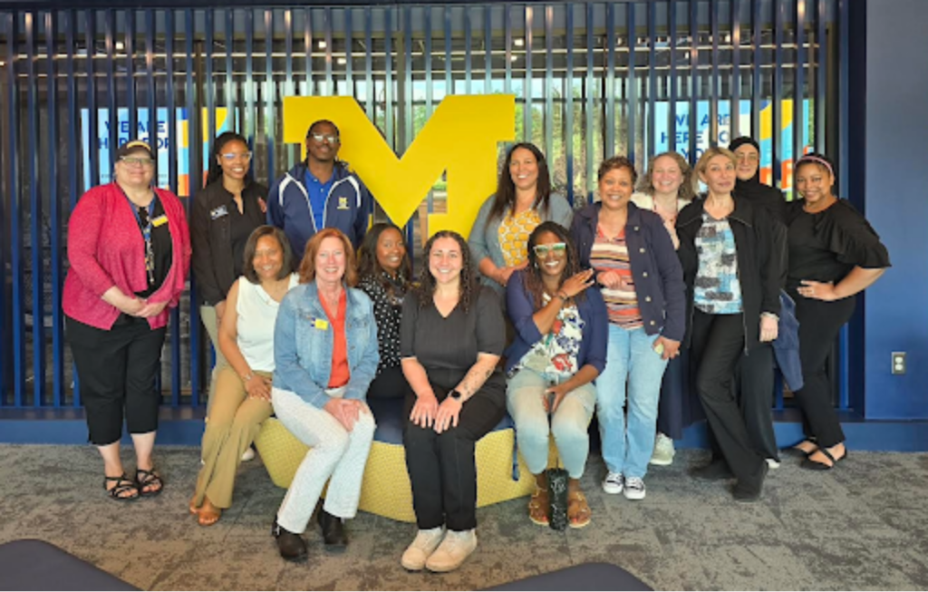 A group of career services professionals posing for a photo in front of a block M. 