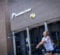 A young woman in a gray t-shirt and black shorts is preparing to hit a volleyball outside a building labeled "Recreation Center."