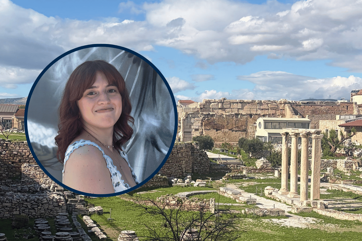 A portrait of a woman with wavy brown hair, smiling, is overlaid on a scenic view of ancient ruins with columns and stone structures under a blue sky.