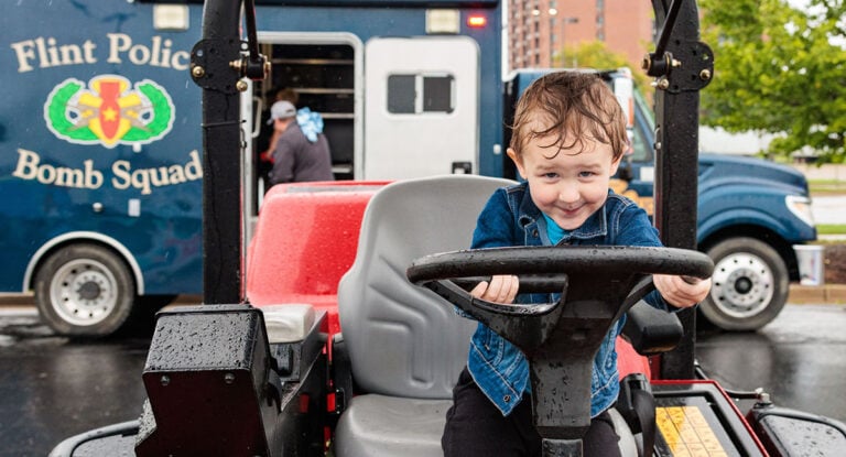Attendees explore emergency and service vehicles during the University of Michigan-Flint Department of Public Safety Touch-a-Truck event.
