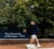 A person walks past a sign that reads "The University of Michigan - Flint," surrounded by trees.