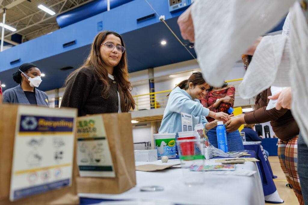 A group of people participating in an activity at a community event, with tables displaying various materials and supplies.
