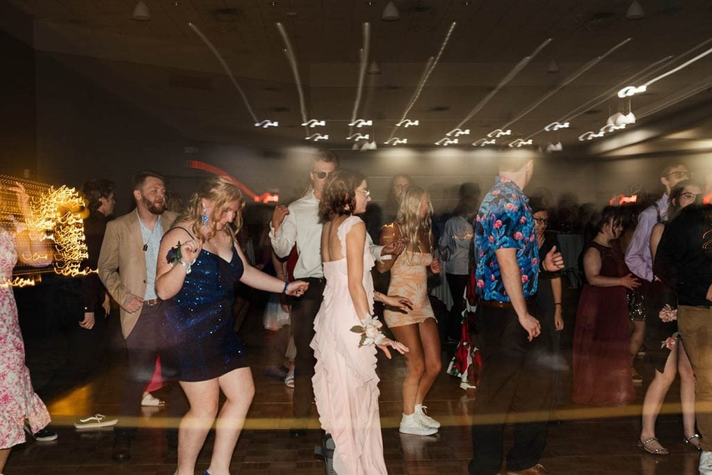 A group of people dancing on a dance floor with moving lights.